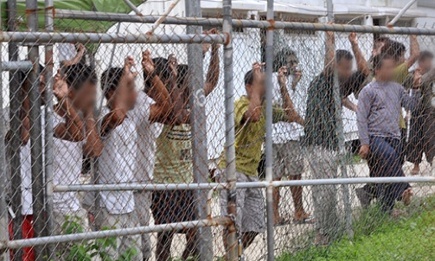 Asylum seekers stand behind a fence in Oscar compound at the Manus Island detention centre in Papua New Guinea.