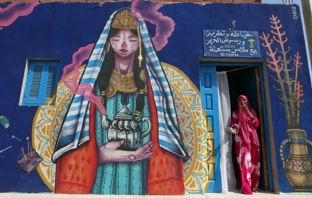 A seamstress stands at the entrance of her workshop decorated by Spanish artist Malakkai