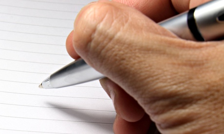 A hand holding a pen above a blank page of a spiral notebook.