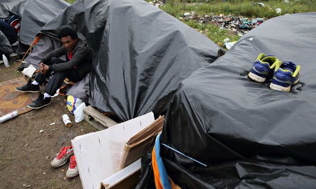 An Eritrean migrant sits outside his makeshift shelter close to a chemical factory in Calais