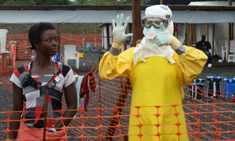 A medical worker gestures beside a woman inside a high-risk area where Ebola patients are being treated in Monrovia, Liberia.