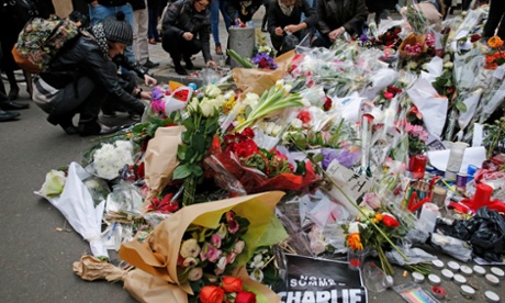 People gather to place candles and flowers as they continue to pay tribute to the shooting victims in front of the offices of the weekly satirical newspaper Charlie Hebdo in Paris on 10 January 2015.