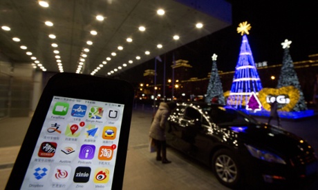 The Uber app is displayed on a phone posed for photos near a woman peering into a car outside a office building in Beijing, Friday, Jan. 9, 2015.