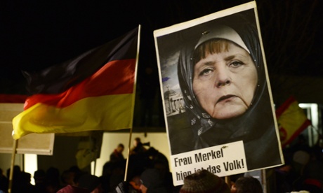 An image of Angela Merkel manipulated to make it look like she's wearing a hijab, at a Pegida rally in Dresden.