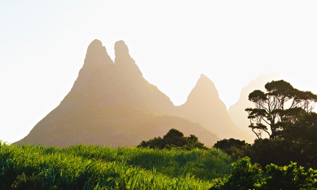 The Mamelles peaks tower over a sugar cane plantation.