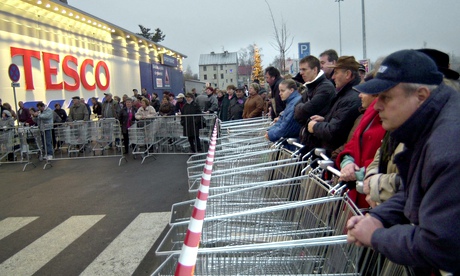 Customers with shopping carriages stand ready
