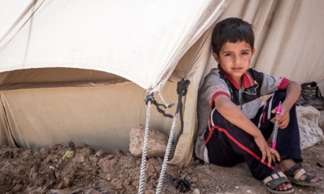 A young Syrian boy sits in front of his family's tent in a refugee camp in northern Iraq.