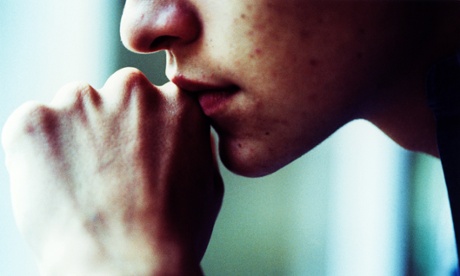 Depressed teenager resting mouth on hands.