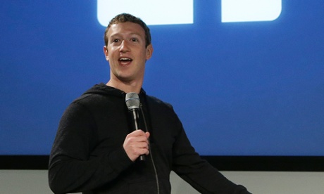 Mark Zuckerberg on stage in front of a Facebook logo.