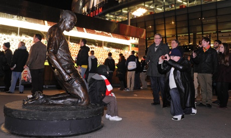Bronze statue of Thierry Henry, kneeling, with Emirates stadium in background