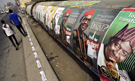 People walk past poster of Nigerian Pres