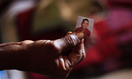 A woman holds a picture of her husband