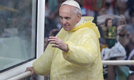 Pope Francis in yellow rain mac waves to the crowd during a motorcade in Manila, Philippines