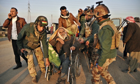 Kurdish soldiers help move an elderly Yazidi after around 200 captives were released by Isis militan