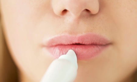 A girl applies lip balm