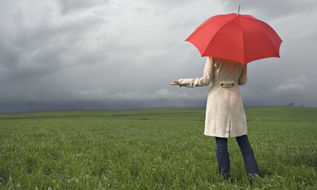 Rear view of woman holding umbrella in field under cloud