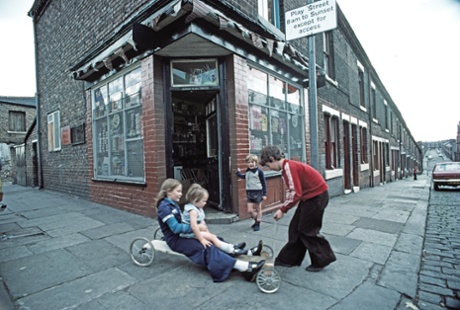 Children playing on a home-made go-cart outside a corner shop in Manchester, 1977.