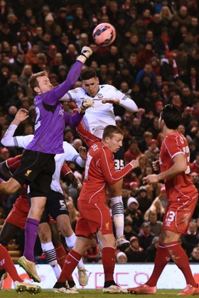 Liverpool's goalkeeper Simon Mignolet punches the ball clear under pressure from Bolton Wanderers' English striker Conor Wilkinson.