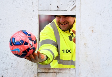 A member of the club's staff throws the ball back after retrieving it from the building site adjoining the pitch.