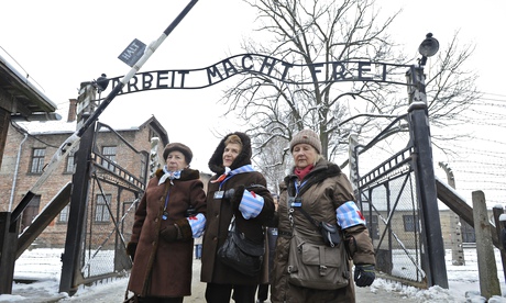 Holocaust survivors walk outside the gate of the Auschwitz 