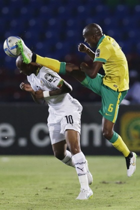 Ghana's Andre Ayew, left, bravely goes in for a challenge with the flying boot of South Africa's Anele Ngcongca,