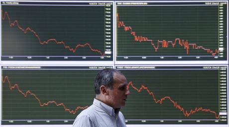 An employee of the Stock Exchange walks next to a display showing stock price movements in Athens, Wednesday, Jan. 28, 2015.