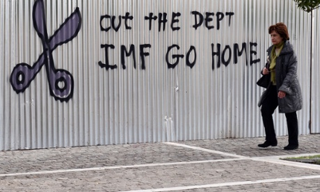 A woman walks past a slogan in central Athens.