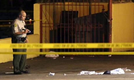 A Los Angeles sheriff's deputy inspects the scene where a man was killed in a hit-and-run involving the rap music mogul Marion 'Suge' Knight.