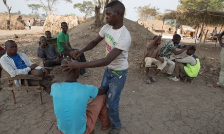 A refugee gets a haircut at the unofficial camp by  the river Ubangi.