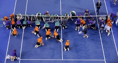 Ground staff dry the court surface during the rain delay.