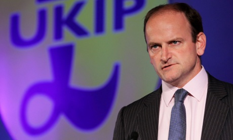 Douglas Carswell  looking stern in front of a Ukip sign