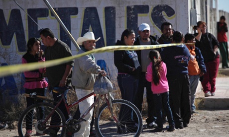Onlookers stand near the police cordon at a crime scene where a man was gunned down by unknown assailants in Ciudad Juarez.