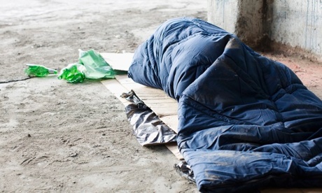 Homeless man sleeping in sleeping bag on cardboard