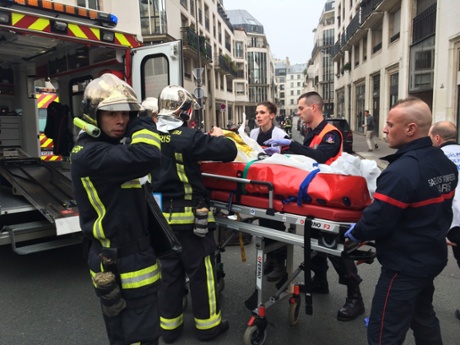 Firefighters carry an injured man out of the Charlie Hebdo offices