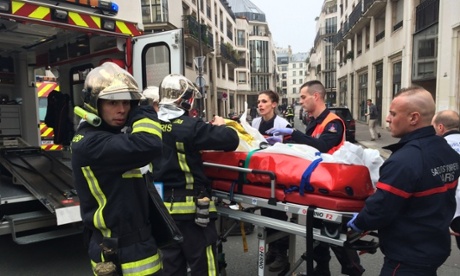 Firefighters carry an injured man outside of the offices of the Charlie Hebdo offices in Paris