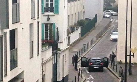 Armed men face police officers near the offices of Charlie Hebdo