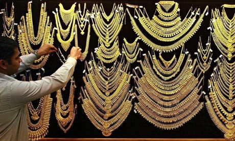A salesman arranges a gold necklace inside a gold jewellery shop 