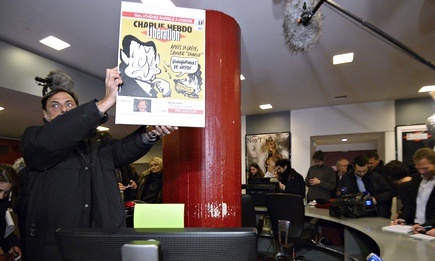 A man holds the cover of an issue of Libération bearing the name of Charlie Hebdo, as the magazine's staff gathered for the first time following Wednesday's massacre