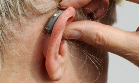 Modern small hearing aid behind the ear of a woman.