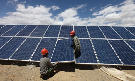 Workers install a solar panel at a photovoltaic power station in Aleteng village, northwest China. Job creation is an example of an economic co-benefit of tackling climate change.