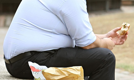 An overweight man eating fast food