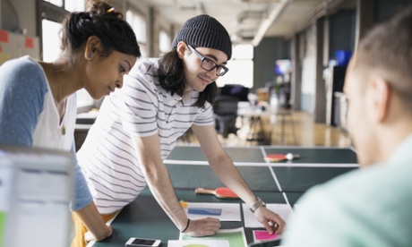 Colleagues in an office have a discussion over a table tennis table