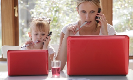 A daughter copies her mother as she works on a laptop