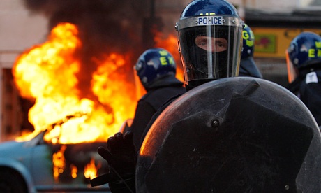 Riot police in front of a burning car in Hackney during the 2011 riots