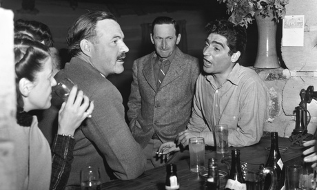 Hemingway drinking in a bar, talking to photojournalist Robert Capa in 1940