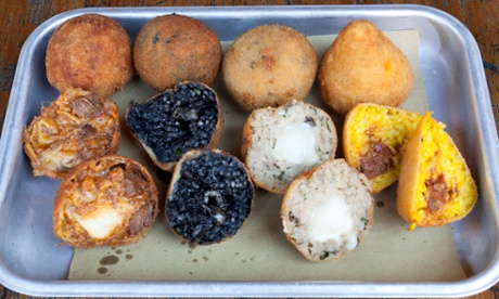 Arancini platter with three rows of four fried items, some split open to show their insides