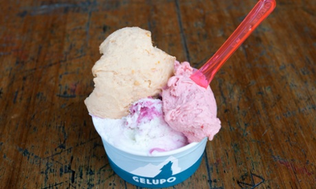 A paper cup with a scoop each of ricotta sour cherry, strawberry and apricot ice cream, a plastic spoon sticking out