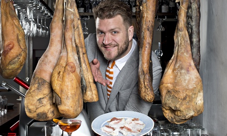 Daniel Willis of the Clove Club pictured between hanging meats offering a dish