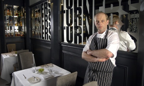Richard Turner leaning back, arms folded, unsmiling, inside his restaurant, Turner's, in Birmingham