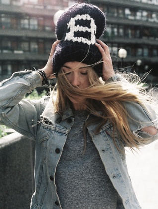 A woman holding her Count On Me Beanie on her head in the wind